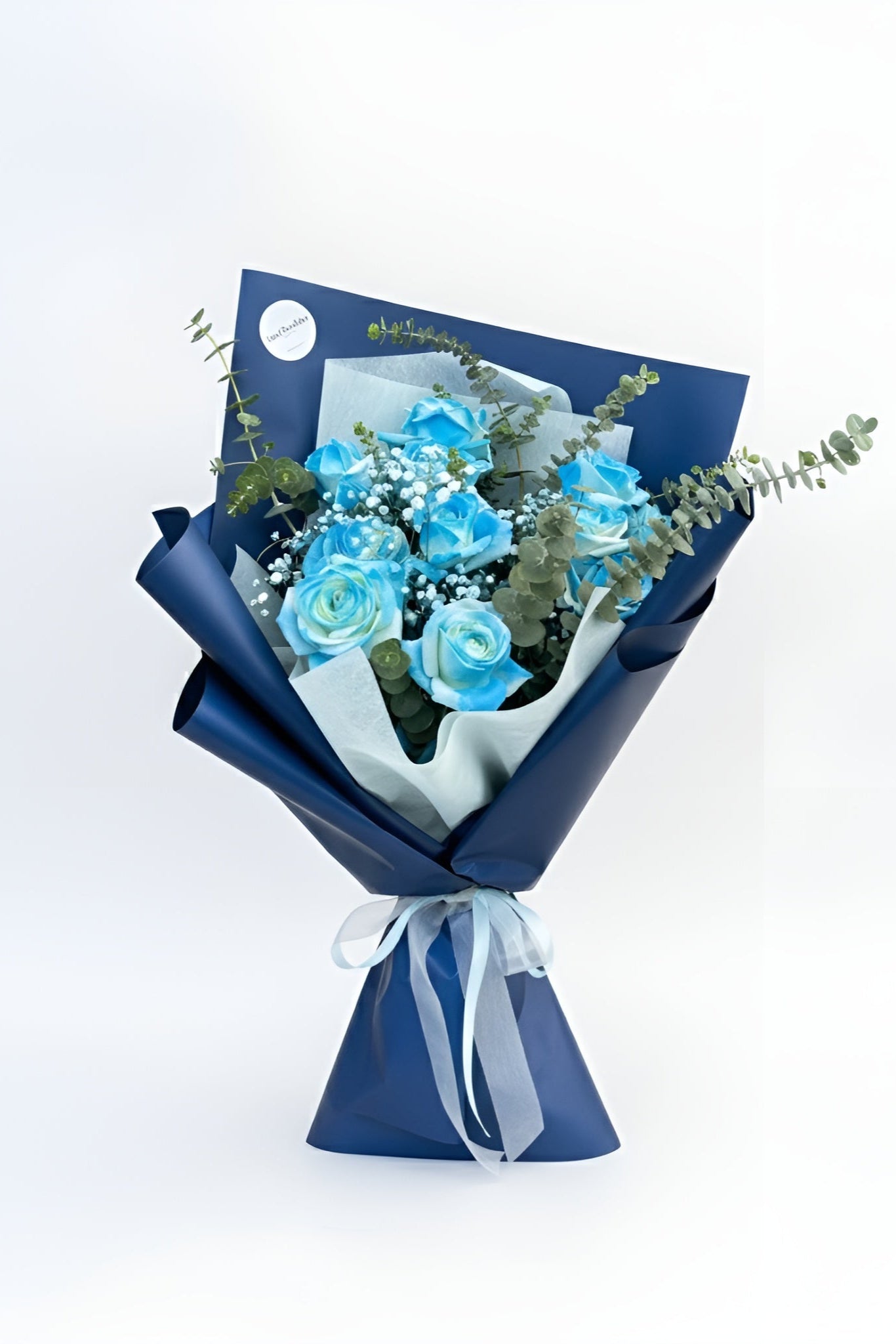 Bouquet of blue flowers wrapped in navy paper with a white ribbon on a white background