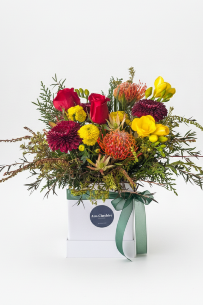 Bouquet of colorful flowers in a box with a visible brand label on a white background