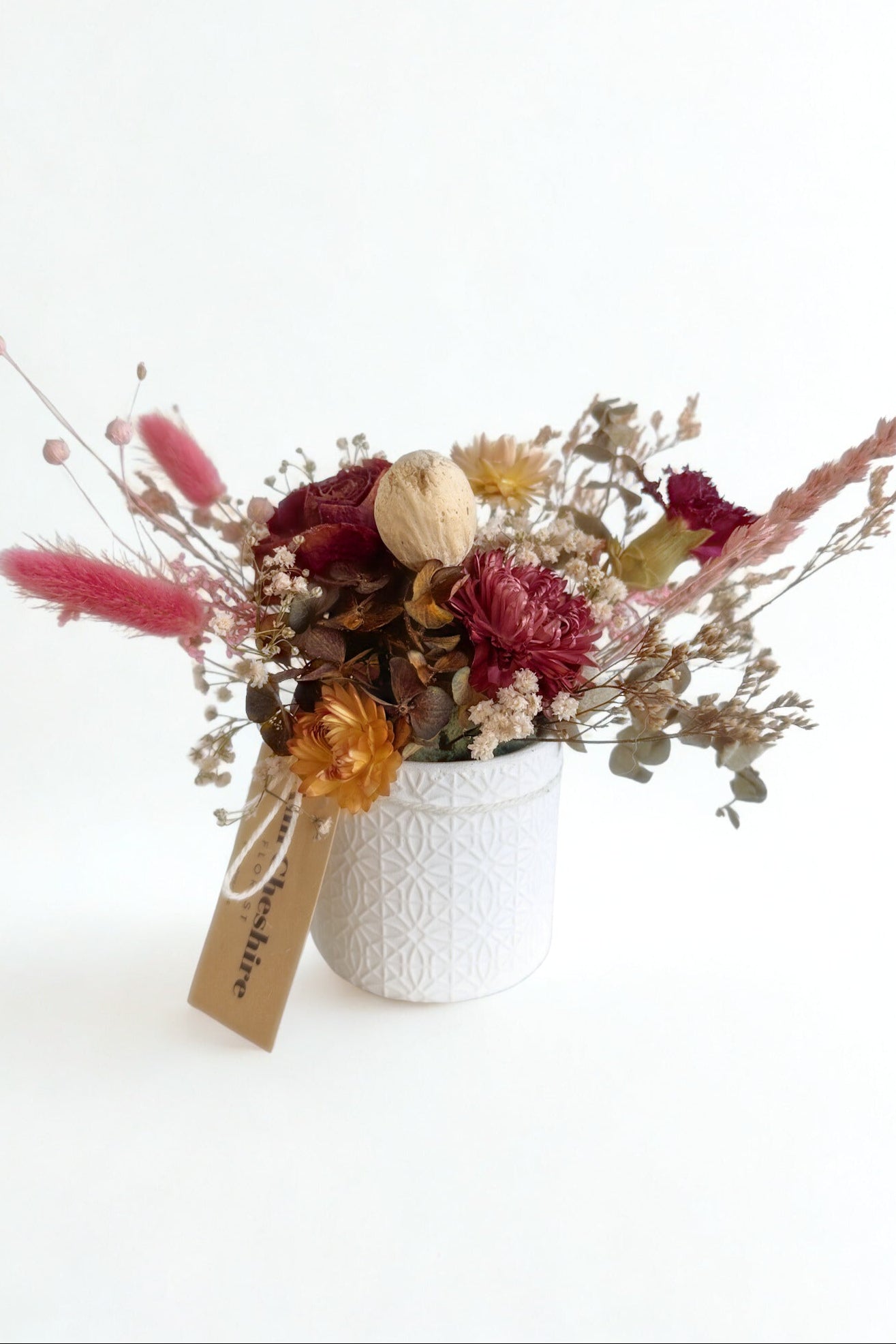 Bouquet of dried flowers in a white vase on a white background