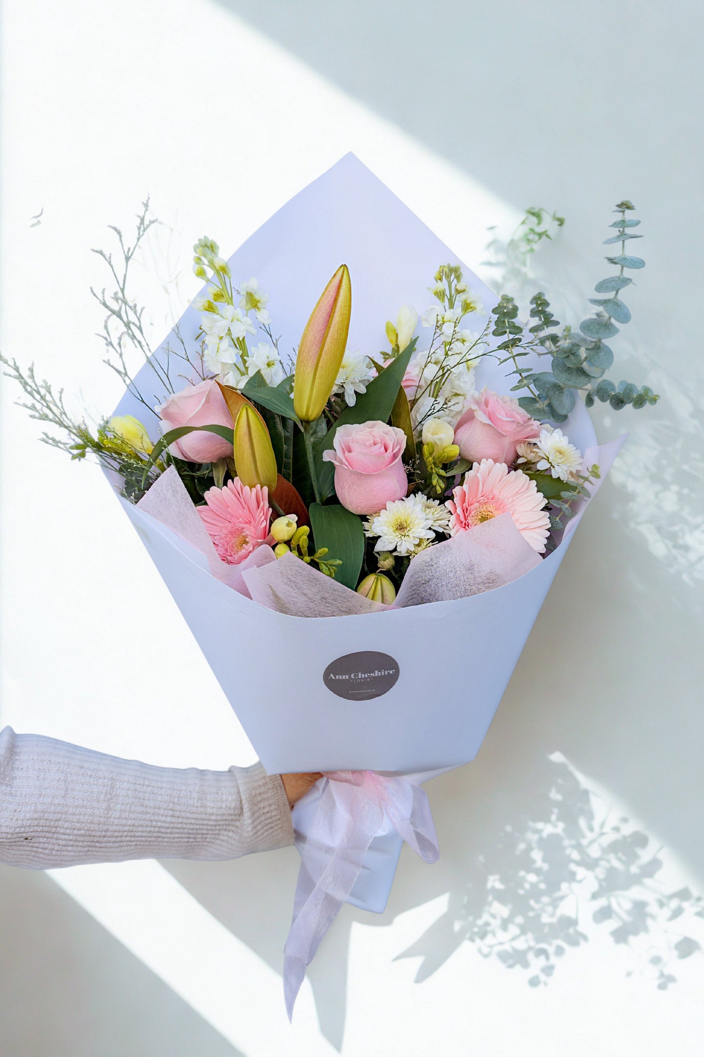 Bouquet of flowers held by a person with a light background