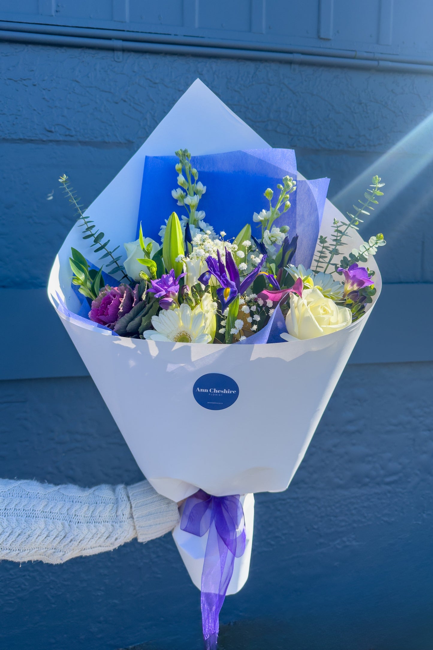Bouquet of flowers held against a blue background