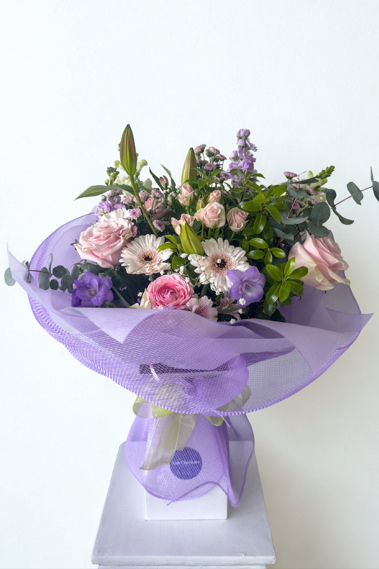 Bouquet of flowers wrapped in purple paper on a white background