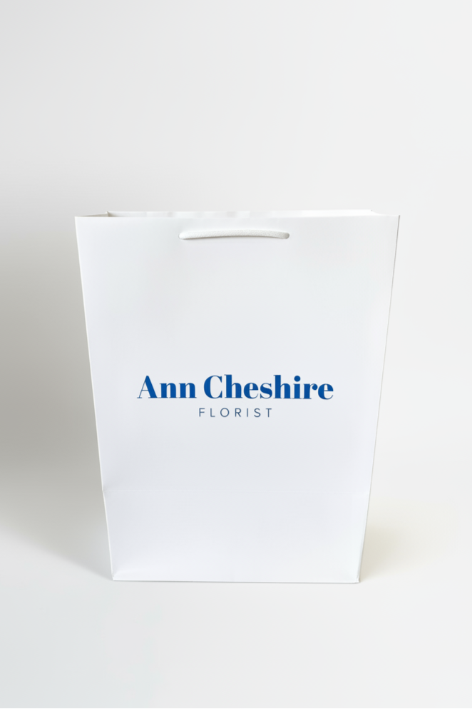 White paper bag with 'Ann Cheshire Florist' text on a white background