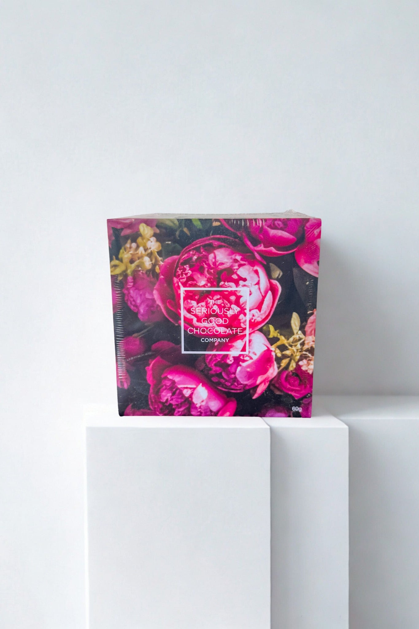 Floral chocolate with a pink rose design on a white pedestal against a light gray background