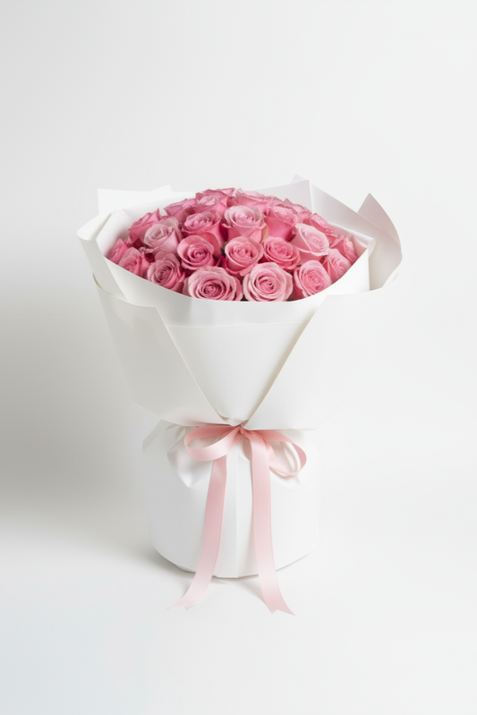 Bouquet of pink roses wrapped in white paper with a pink ribbon on a light gray background