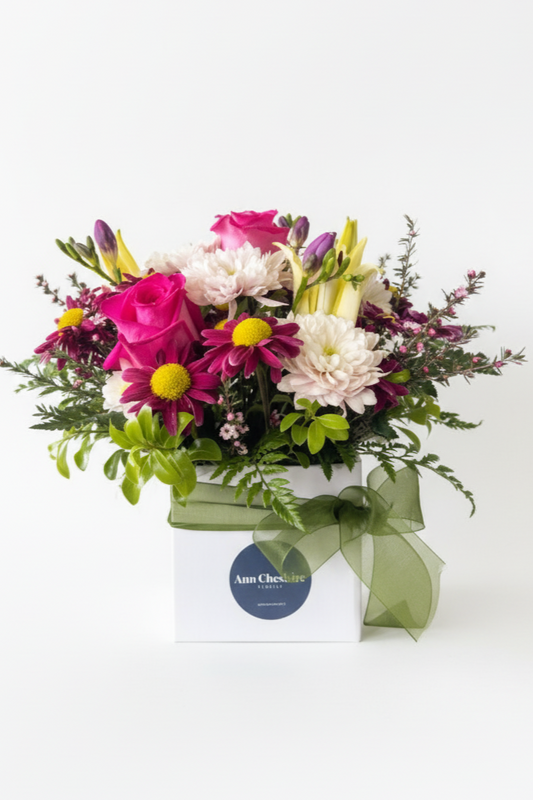 Colorful bouquet of flowers in a box with a visible brand label on a white background