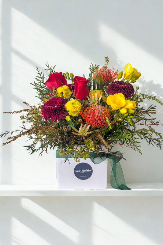 Colorful bouquet of flowers in a box on a white surface with a light background