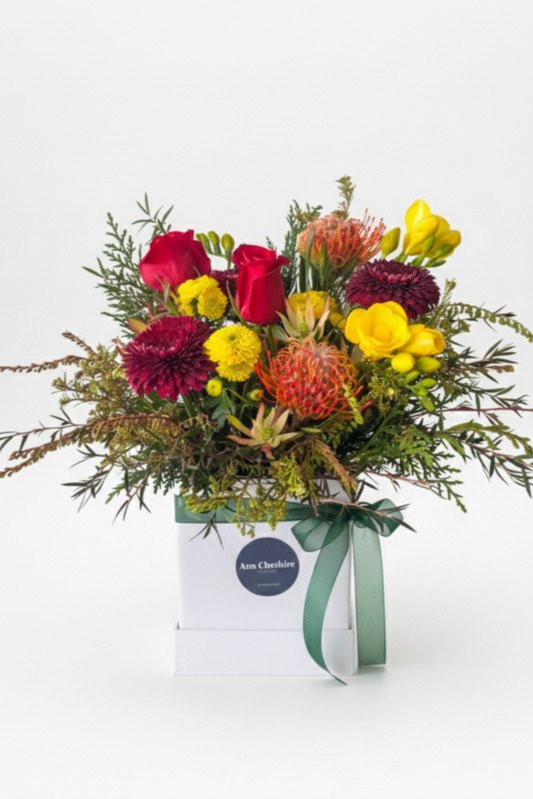 Bouquet of colorful flowers in a box with a visible brand label on a white background
