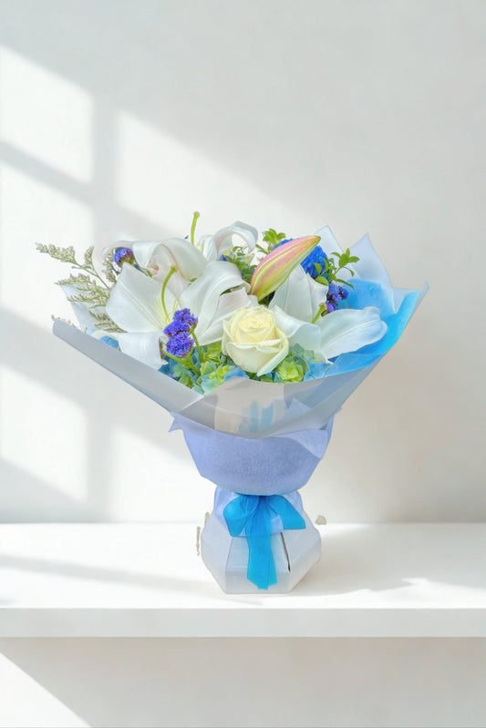 Bouquet of flowers wrapped in blue paper on a white surface with a light background