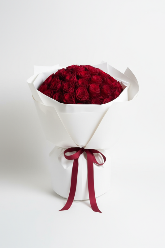 Bouquet of red roses in a white cone with a red ribbon on a white background