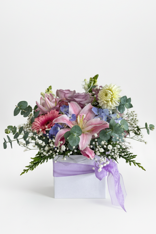 Floral arrangement in a box with a purple ribbon on a white background