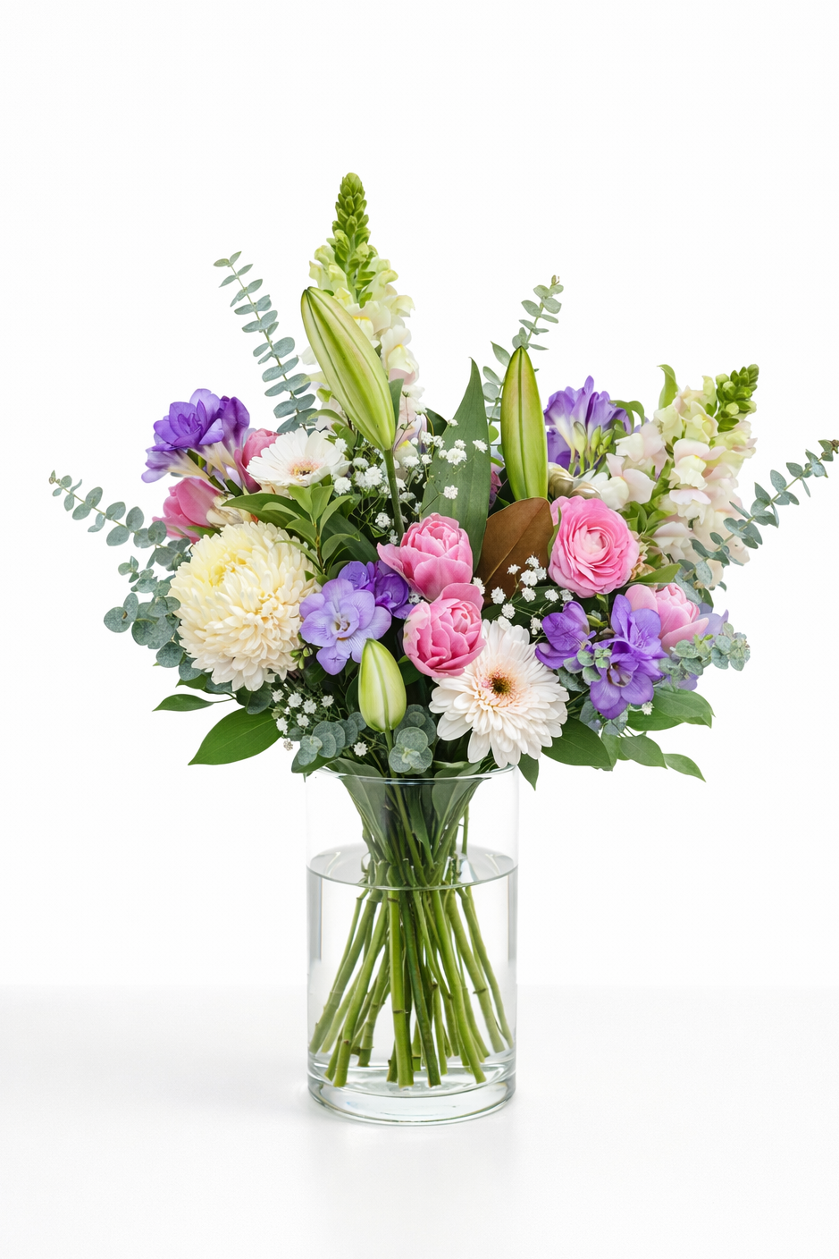 Bouquet of colorful flowers in a clear vase on a white background