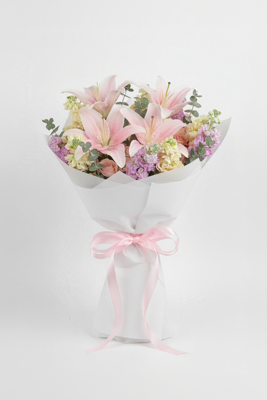 Bouquet of flowers wrapped in white paper with a pink ribbon on a light background