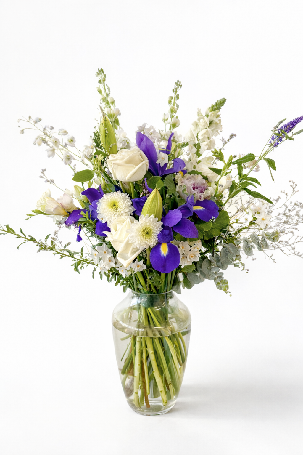 Bouquet of flowers with purple and white flowers in a clear vase on a white background