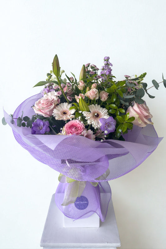 Bouquet of flowers wrapped in purple paper on a white background