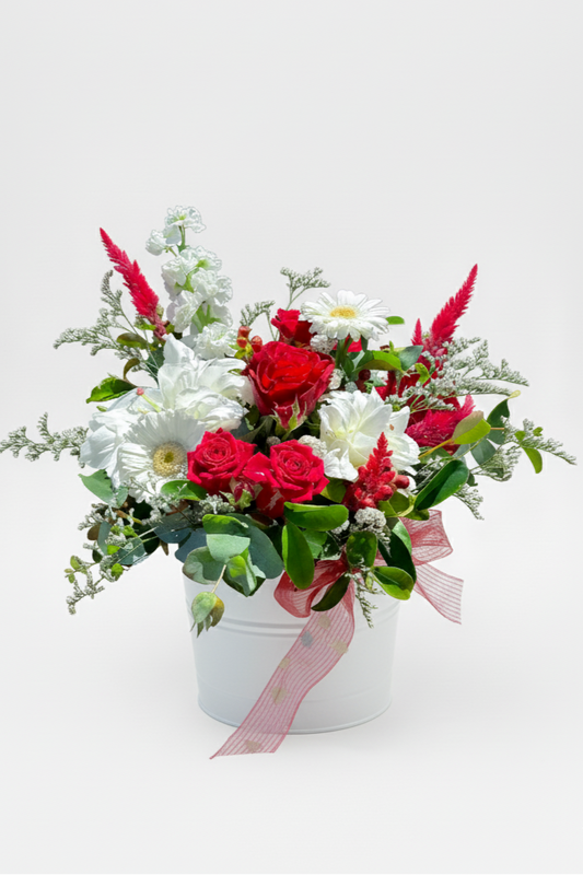 Floral arrangement with red and white flowers in a white container on a light gray background