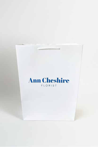 White paper bag with 'Ann Cheshire Florist' text on a white background