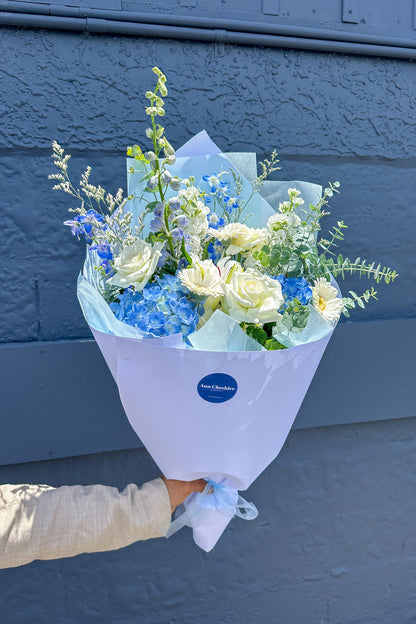 Bouquet of flowers held against a blue wall